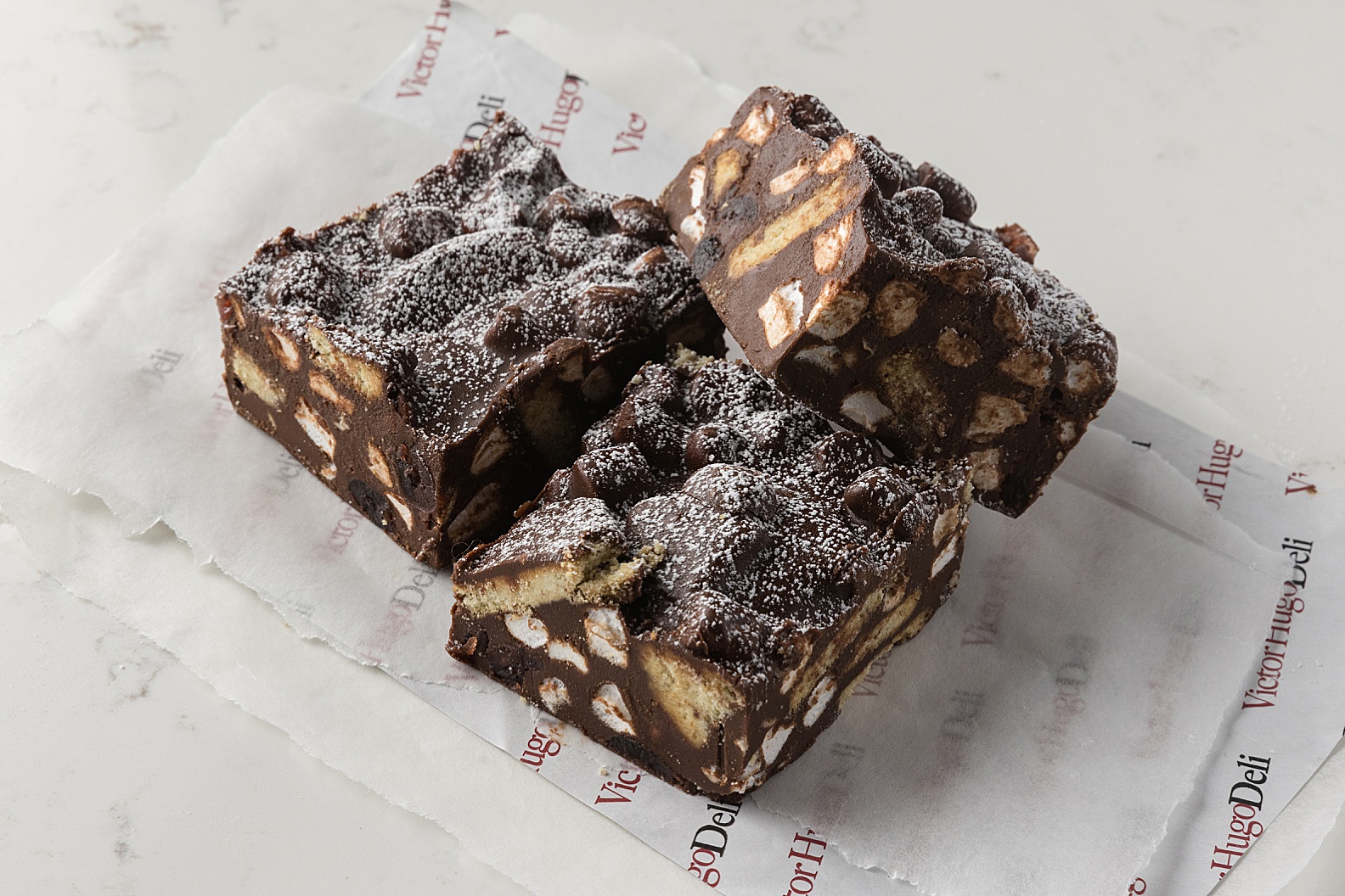 Three slices of dark chocolate rocky road with biscuit and marshmallow chunks