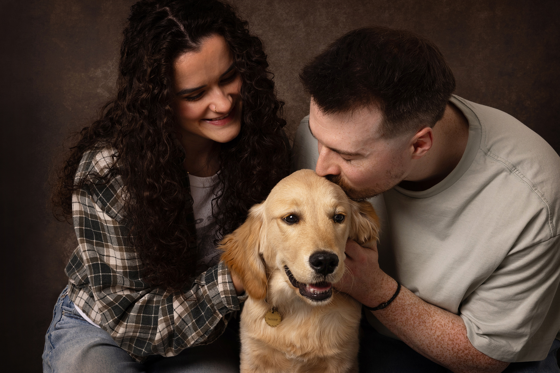 Photograph of couple cuddling a puppy Labrador, taken in a studio